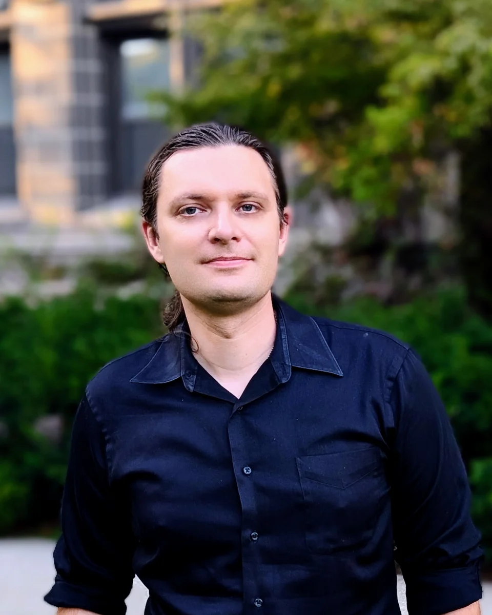 Sarunas Verner, outdoors in front of a stone building and greenery